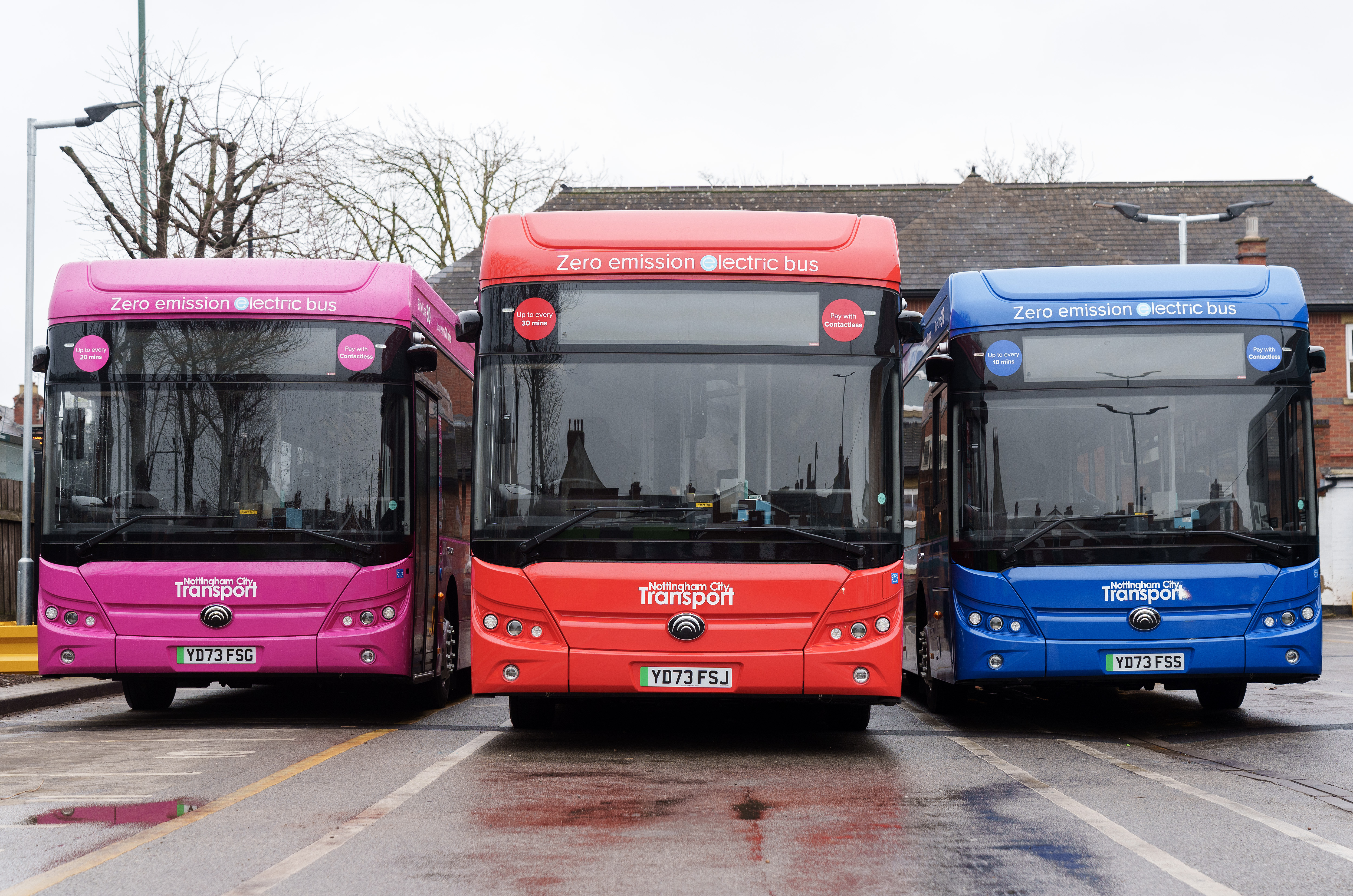 NCT electric buses in three colours - red, blue and pink, parked at NCT's depot